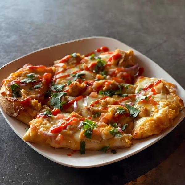 A Lodge on Main flatbread pizza with chicken, cheese, red sauce, and cilantro on a white plate.