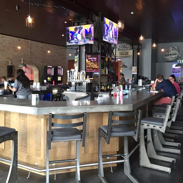 The Lodge on Main's bar area with patrons, a bartender, and multiple TVs showing sports.